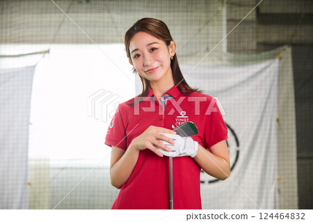 A woman practicing at an indoor golf driving range 124464832