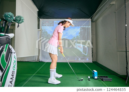 一名女子在室內高爾夫練習場練習 124464835