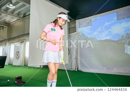 一名女子在室內高爾夫練習場練習 一名女子在室內高爾夫練習場練習 124464838