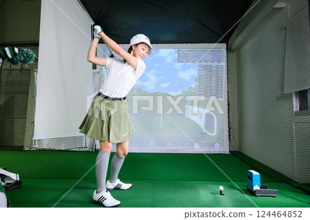 一名女子在室內高爾夫練習場練習 一名女子在室內高爾夫練習場練習 124464852