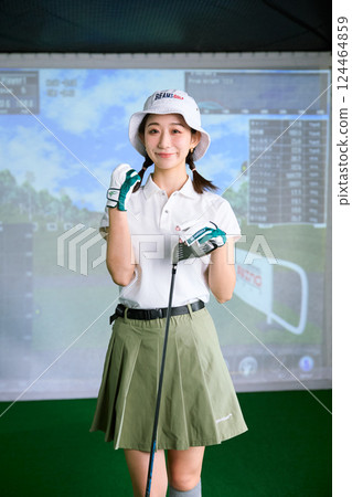 A woman practicing at an indoor golf driving range 124464859