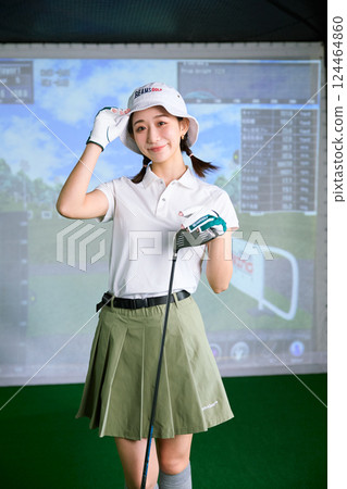 A woman practicing at an indoor golf driving range 124464860