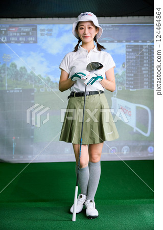 一名女子在室內高爾夫練習場練習 一名女子在室內高爾夫練習場練習 124464864