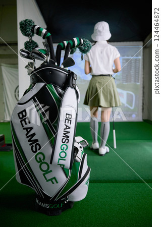 A woman practicing at an indoor golf driving range A woman practicing at an indoor golf driving range 124464872