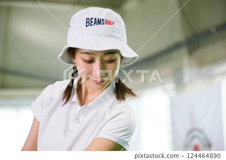A woman practicing at an indoor golf driving range 124464890