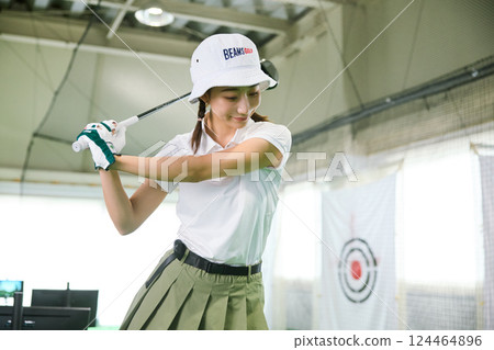 一名女子在室內高爾夫練習場練習 124464896