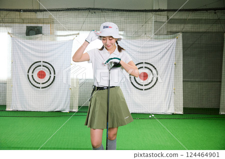一名女子在室內高爾夫練習場練習 一名女子在室內高爾夫練習場練習 124464901