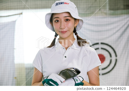 A woman practicing at an indoor golf driving range A woman practicing at an indoor golf driving range 124464920