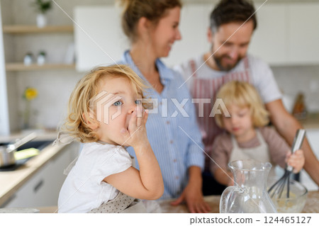 Young nuclear family making pancakes together. Parents and children in kitchen, preparing pancake batter, spending weekend day indoors. 124465127