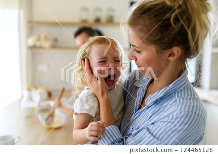 Little girl crying and screaming, mother holding her in arms and soothing her. 124465128