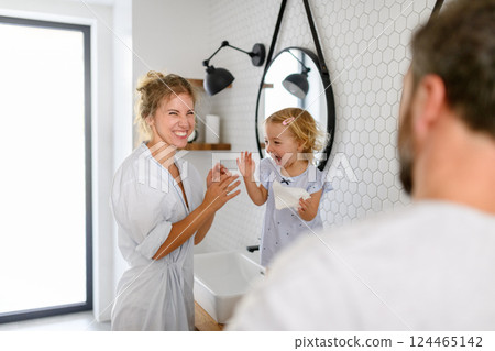 Parents and daughter having morning bathroom routine, brushing teeth and washing face, enjoying together time. Parents and daughter having morning bathroom routine, brushing teeth and washing face, enjoying together time. 124465142