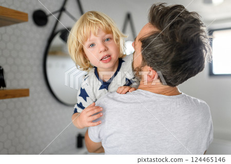 Father holding son in arms, standing in bathroom. Morning routine for young boy before going to preschool. Father holding son in arms, standing in bathroom. Morning routine for young boy before going to preschool. 124465146