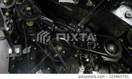 Close-up of the complex mechanism inside a grain harvester, displaying belts, pulleys, and gears actively functioning during grain collection. Close-up of the complex mechanism inside a grain harvester, displaying belts, pulleys, and gears actively functioning during grain collection. 124465791