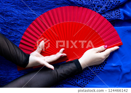 Elegant hand holding red fan on blue fabric background Elegant hand holding red fan on blue fabric background 124466142
