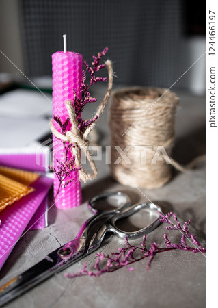Pink beeswax candle with twine wreath on crafting table 124466197
