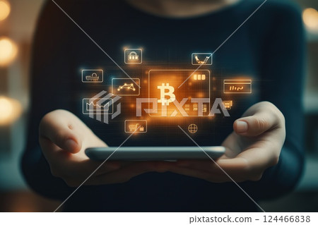 A person holds a tablet displaying bitcoin-related digital icons representing financial transactions 124466838