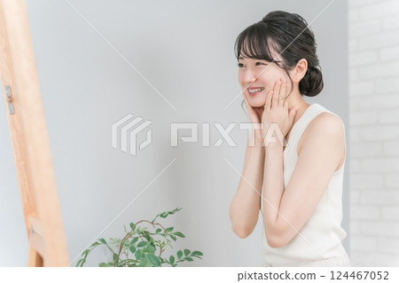 Smiling Asian woman doing skin care and moisturizing 124467052