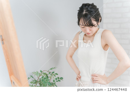 Asian woman suffering from anorexia and weight loss looking at the mirror and checking her waist Asian woman suffering from anorexia and weight loss looking at the mirror and checking her waist 124467448