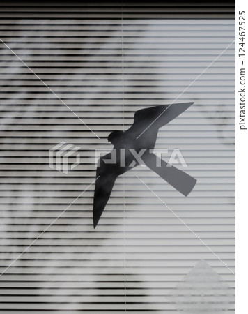 Paper cutout of a swallow fluttering on a windowpane 124467525