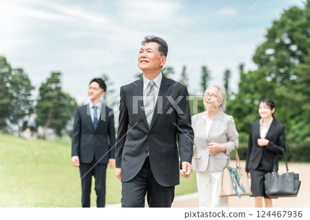 Senior and Gen Z businessmen and women in suits walking in the park 124467936
