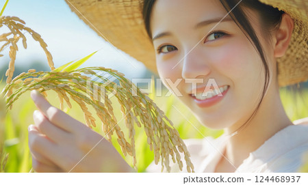 Smiling Japanese woman in a straw hat holding an ear of rice 124468937