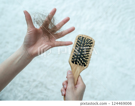 Someone holding a comb with hair loss after brushing hair. 124469006