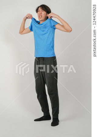 A man flapping his shirt in the heat A man flapping his shirt in the heat 124470928