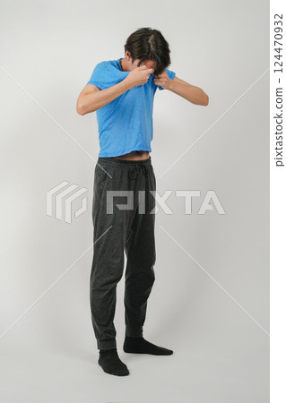 A man wiping sweat from his face with his shirt 124470932