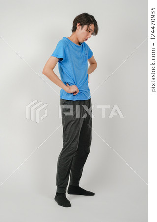 A man with a slightly tired look on his face, with his arms on his hips 124470935