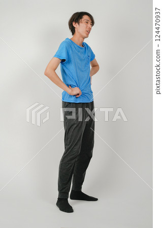 A man with a slightly tired look on his face, with his arms on his hips 124470937