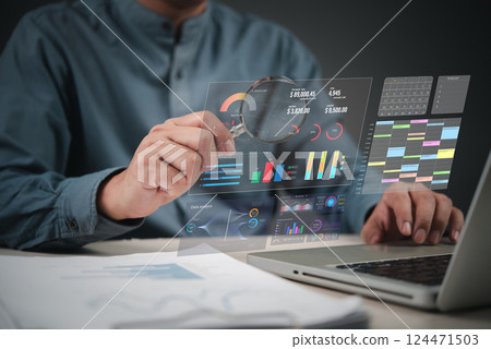Business data dashboard, using laptop and magnifying glass to analyze charts, reports, and statistics for digital marketing and finance. AI analytics, and market research. 124471503