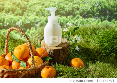 Unlabeled pump bottle placed on the surface of a cut tree stump in the forest. Fresh oranges with dew drops placed in a bamboo basket with handles. Lush green lawn with decorative wildflowers. Unlabeled pump bottle placed on the surface of a cut tree stump in the forest. Fresh oranges with dew drops placed in a bamboo basket with handles. Lush green lawn with decorative wildflowers. 124472291