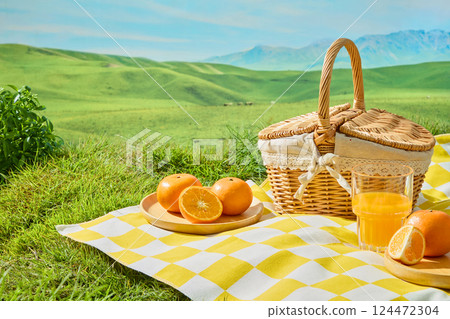 Fresh oranges cut in half and into wedges placed on round wooden plates, presented on white and yellow checkered squares. Wicker baskets with handles and lace trim set against a backdrop of lawns Fresh oranges cut in half and into wedges placed on round wooden plates, presented on white and yellow checkered squares. Wicker baskets with handles and lace trim set against a backdrop of lawns 124472304