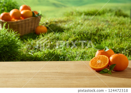 The light-grained wooden floor has fresh oranges with intact stems and rough skin. Orange segment is shiny and juicy in the sunlight. Basket of Citrus is placed on the green grass in the garden. 124472318