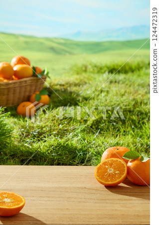 Vertical photo of a natural landscape with ripe oranges in a wicker basket, placed on green meadow. Fresh oranges are cut in half to reveal their juicy flesh. Mountains are visible in the distance. Vertical photo of a natural landscape with ripe oranges in a wicker basket, placed on green meadow. Fresh oranges are cut in half to reveal their juicy flesh. Mountains are visible in the distance. 124472319