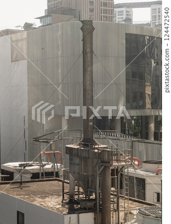 Boiler soot separator chimney on roof of building with modern buildings in the background. Boiler soot separator chimney on roof of building with modern buildings in the background. 124472540