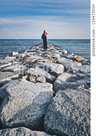 Back view of a woman looking at the sea Back view of a woman looking at the sea 124473050