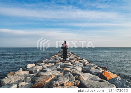 Back view of a woman looking at the sea Back view of a woman looking at the sea 124473053