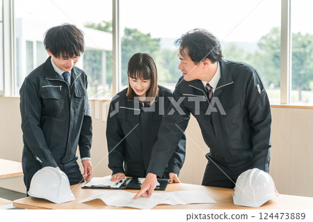 Male and female businessmen in the construction and building industry wearing work clothes having a meeting 124473889