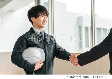 Young Asian men in work clothes shaking hands in a conference room Young Asian men in work clothes shaking hands in a conference room 124474089