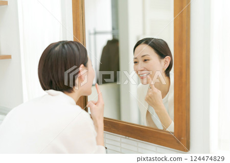 中年婦女在浴室裡看著她的嘴 中年婦女在浴室裡看著她的嘴 124474829