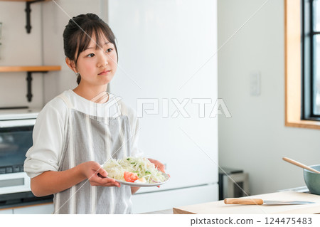 Child, girl, kids holding vegetables in the kitchen (troubled, dislikes vegetables, likes and dislikes) Child, girl, kids holding vegetables in the kitchen (troubled, dislikes vegetables, likes and dislikes) 124475483