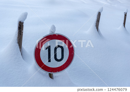 Speed limit road sign covered in snow in the Bavarian Alps, Germany Speed limit road sign covered in snow in the Bavarian Alps, Germany 124476079