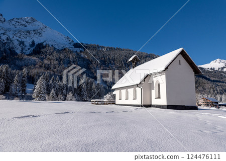 Sunny winter landscape with church minimalist in snow-covered nature Sunny winter landscape with church minimalist in snow-covered nature 124476111