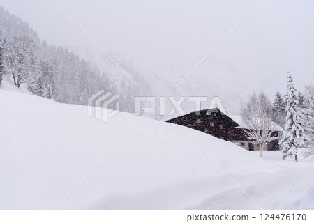 Mountain cabin on a blizzard surrounded by deep snow in the Bavarian Alps, Germany Mountain cabin on a blizzard surrounded by deep snow in the Bavarian Alps, Germany 124476170