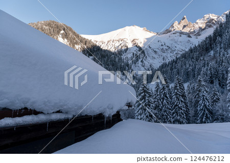 Rustic log cabin covered in deep snow in the Bavarian Alps, in Germany 124476212