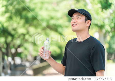A man drinking water/mineral water during exercise (hydration, exercise, workout, running, walking) 124476409