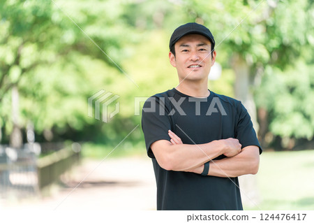 穿著運動服、雙臂交叉在清新綠色公園的亞洲男子 124476417