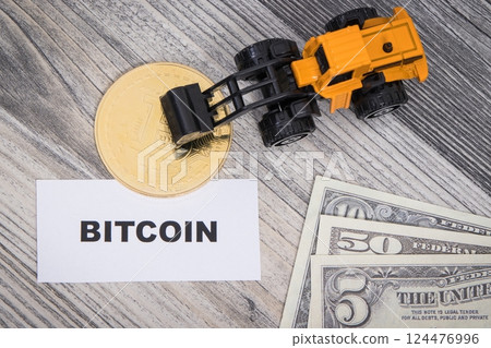 Bitcoin, miniature excavator and dollar bills 124476996