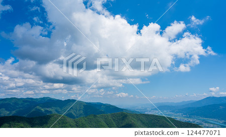 Many white clouds in the blue sky and mountains wrapped in greenery 124477071
